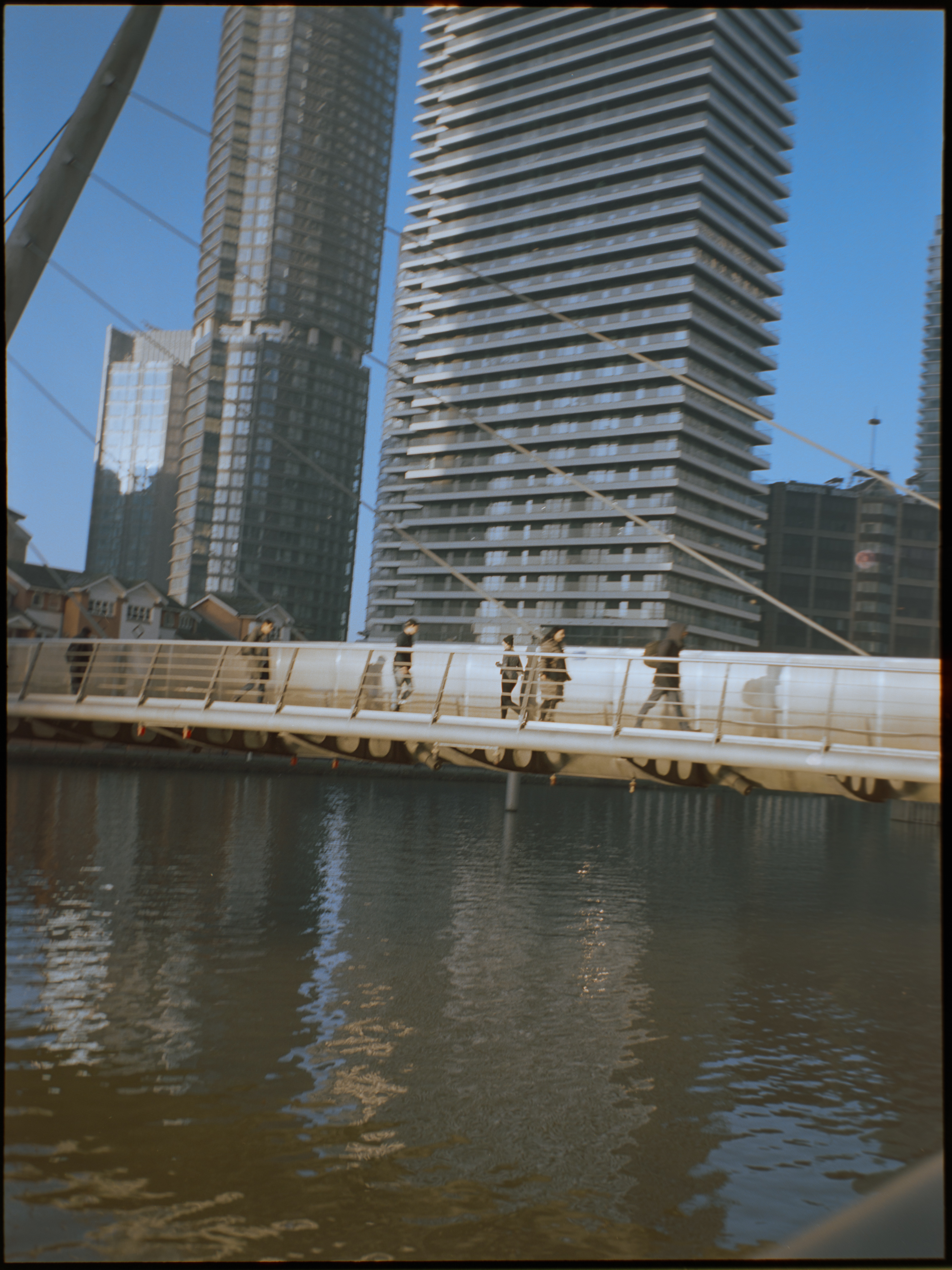 Person walking between modern buildings in Canary Wharf — lifestyle street photography by David McConaghy