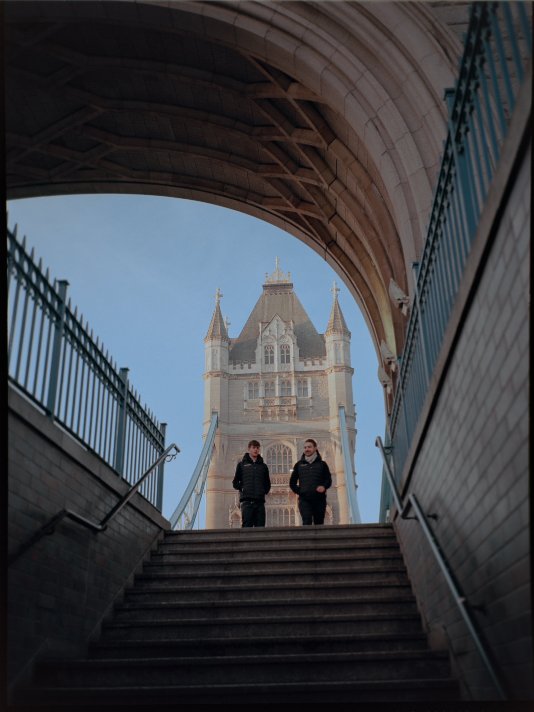 Two men walking down steps under Tower Bridge — medium format street photography London