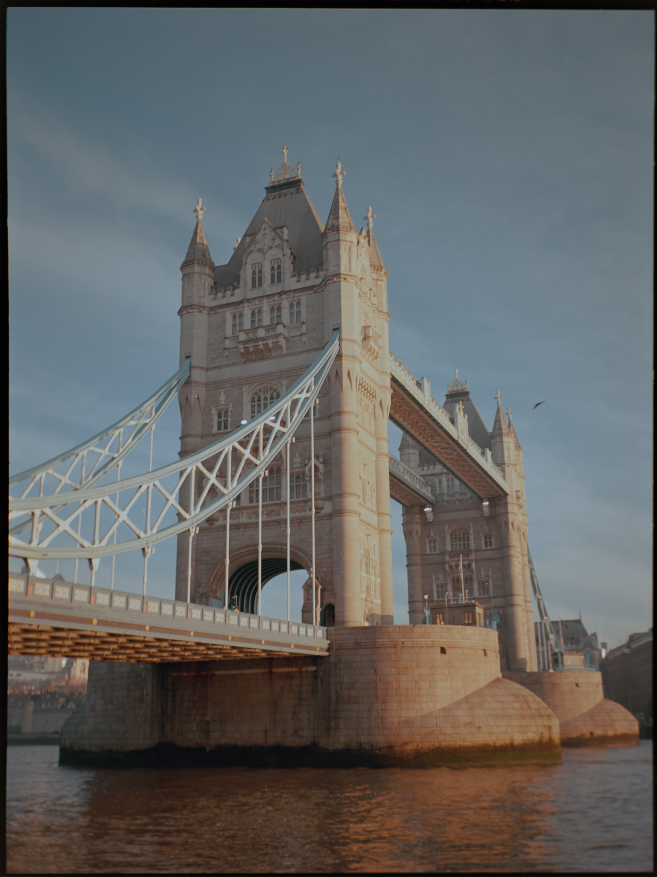 Woman in a red coat walking past Tower Bridge — candid street photography on medium format film by David McConaghy