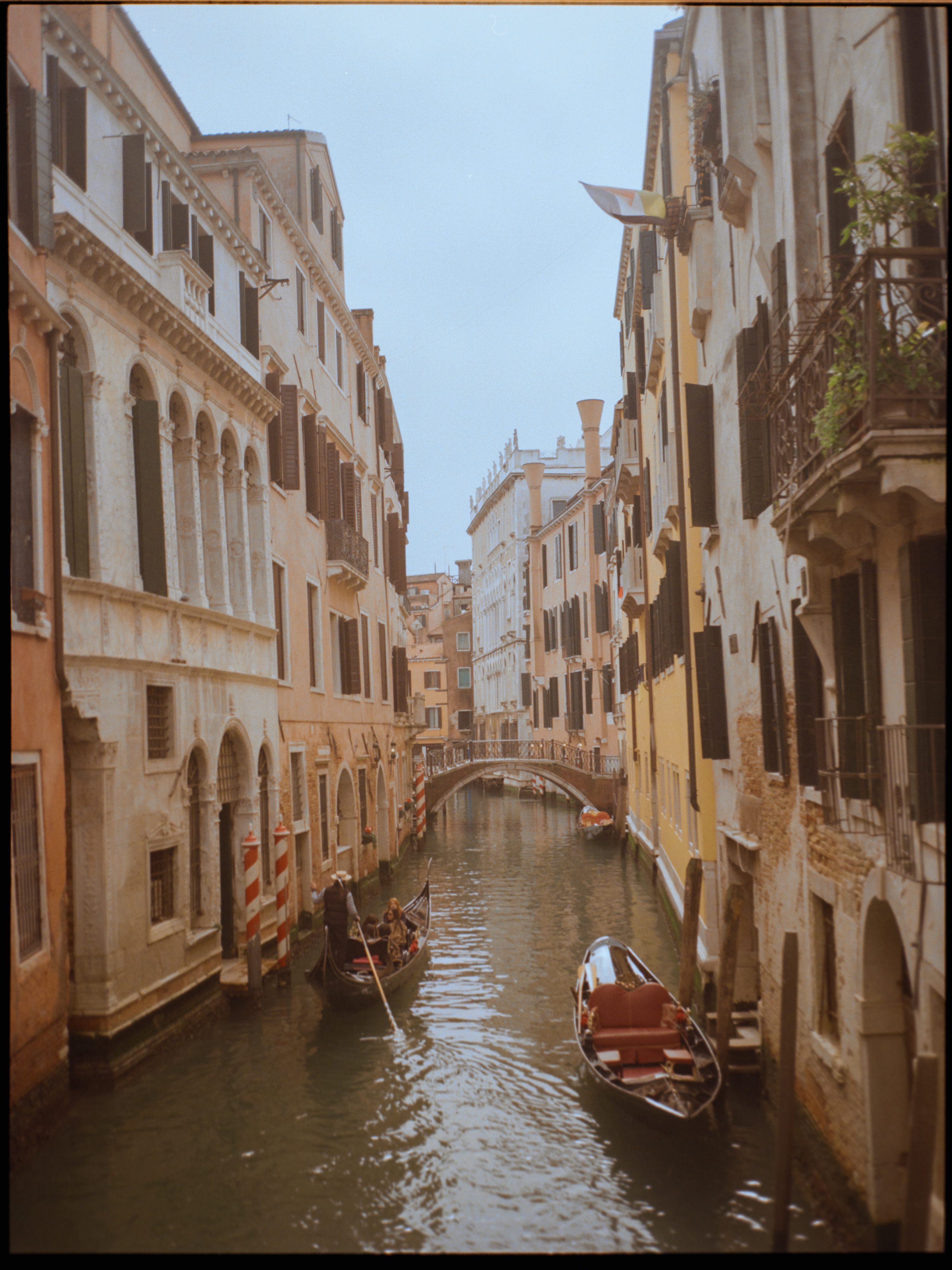 Classic canal view with gondola gliding under a bridge in golden light — Venice on Kodak Gold 200