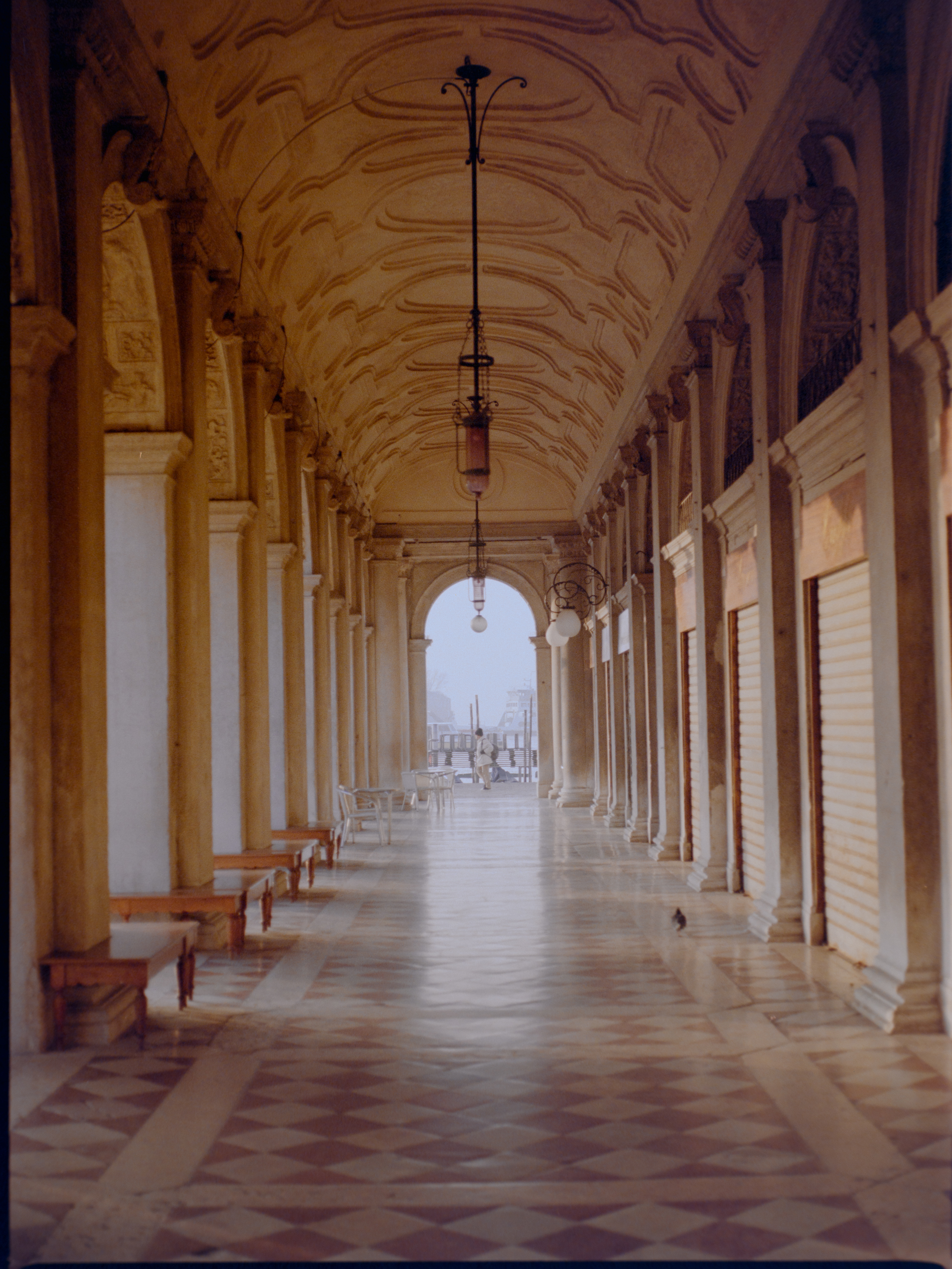 Ornate empty arcade corridor with marble columns and patterned floor — Venice on medium format film