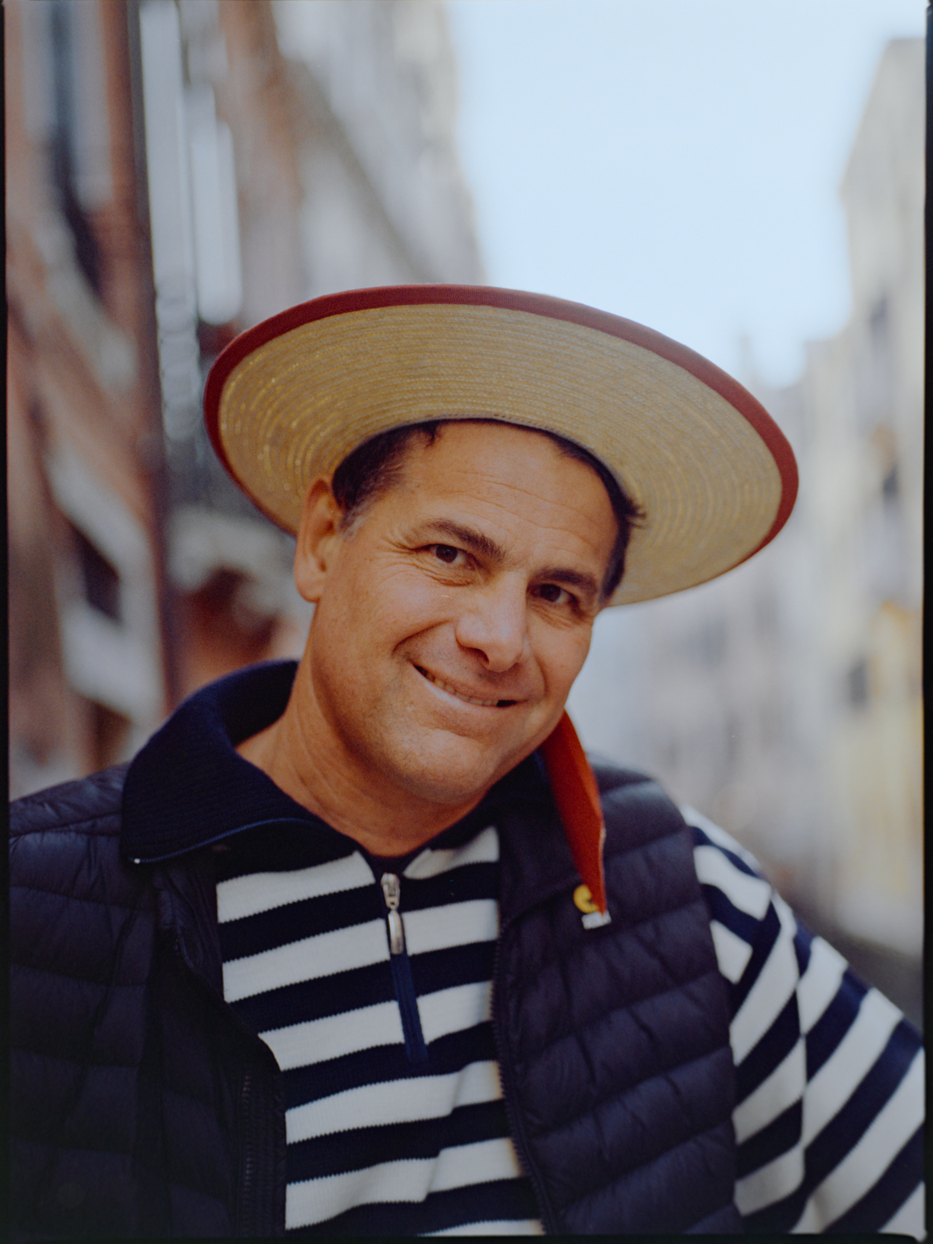 Close-up portrait of an older gondolier smiling in straw hat and striped shirt — Venice portrait on medium format film