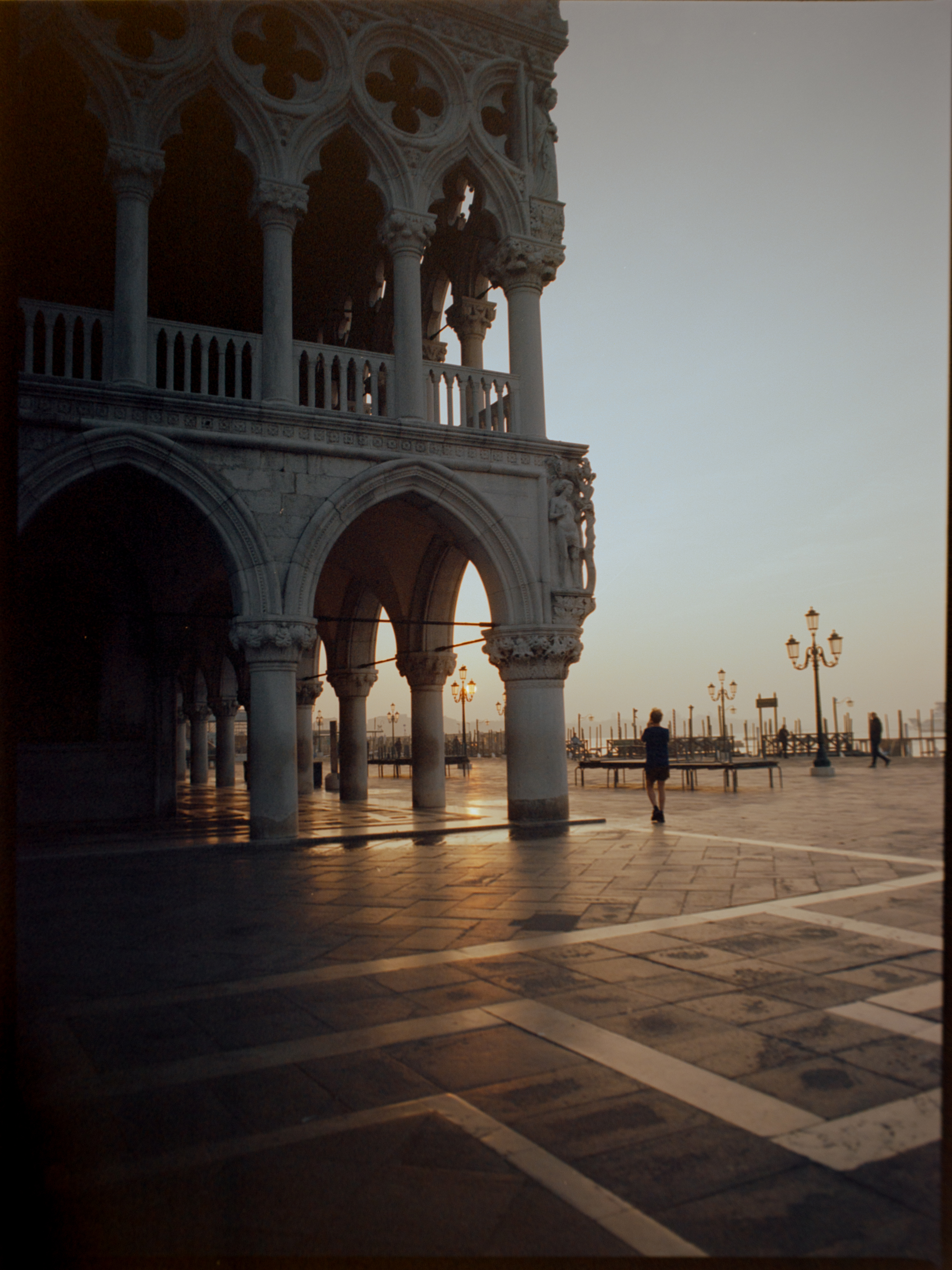 Corner of the Doge's Palace at golden hour with lone figure walking on wet stone — Venice on film