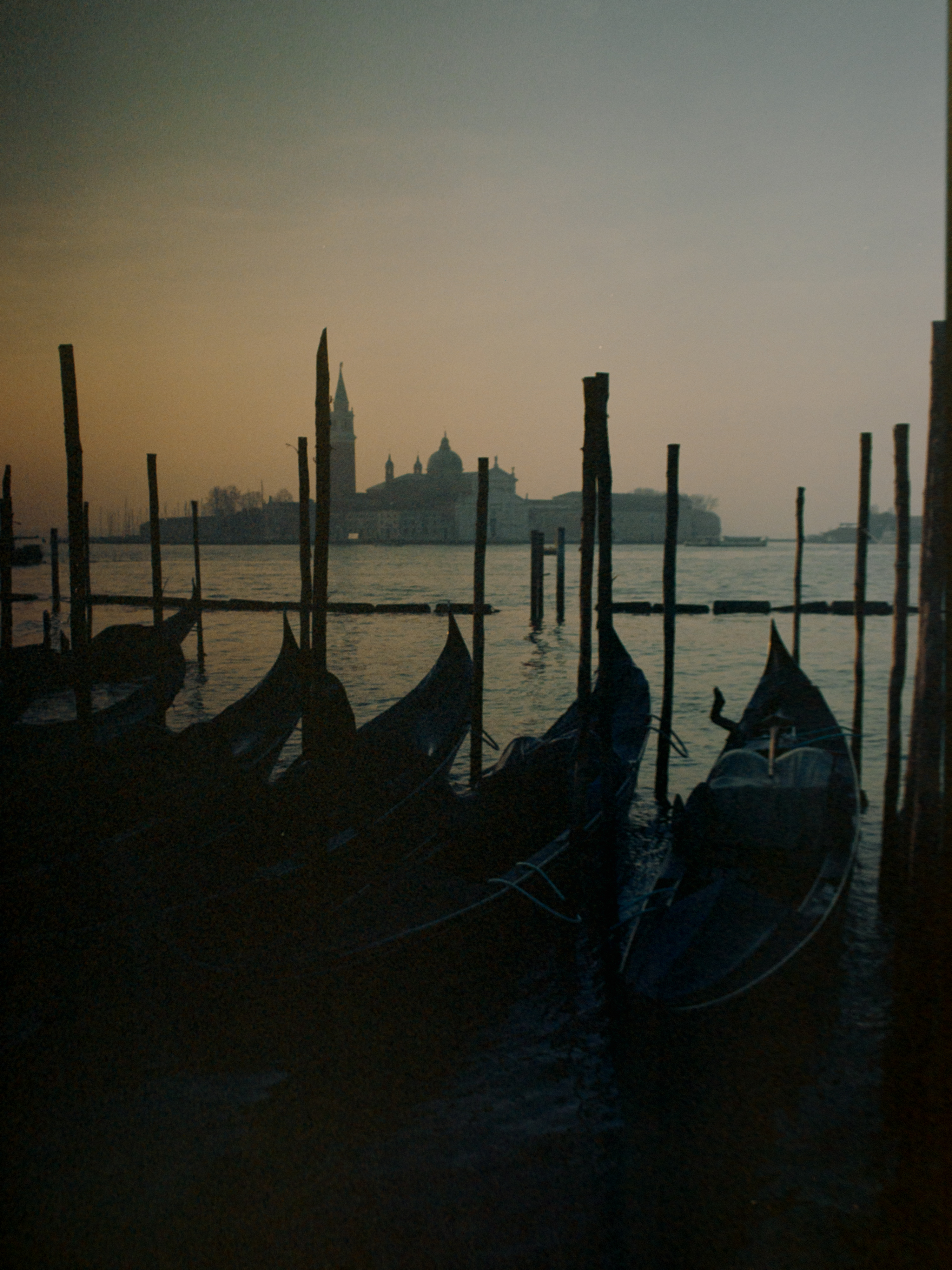 Gondola prows and mooring poles silhouetted against a warm sunset sky — Venice on Kodak Ektar 100