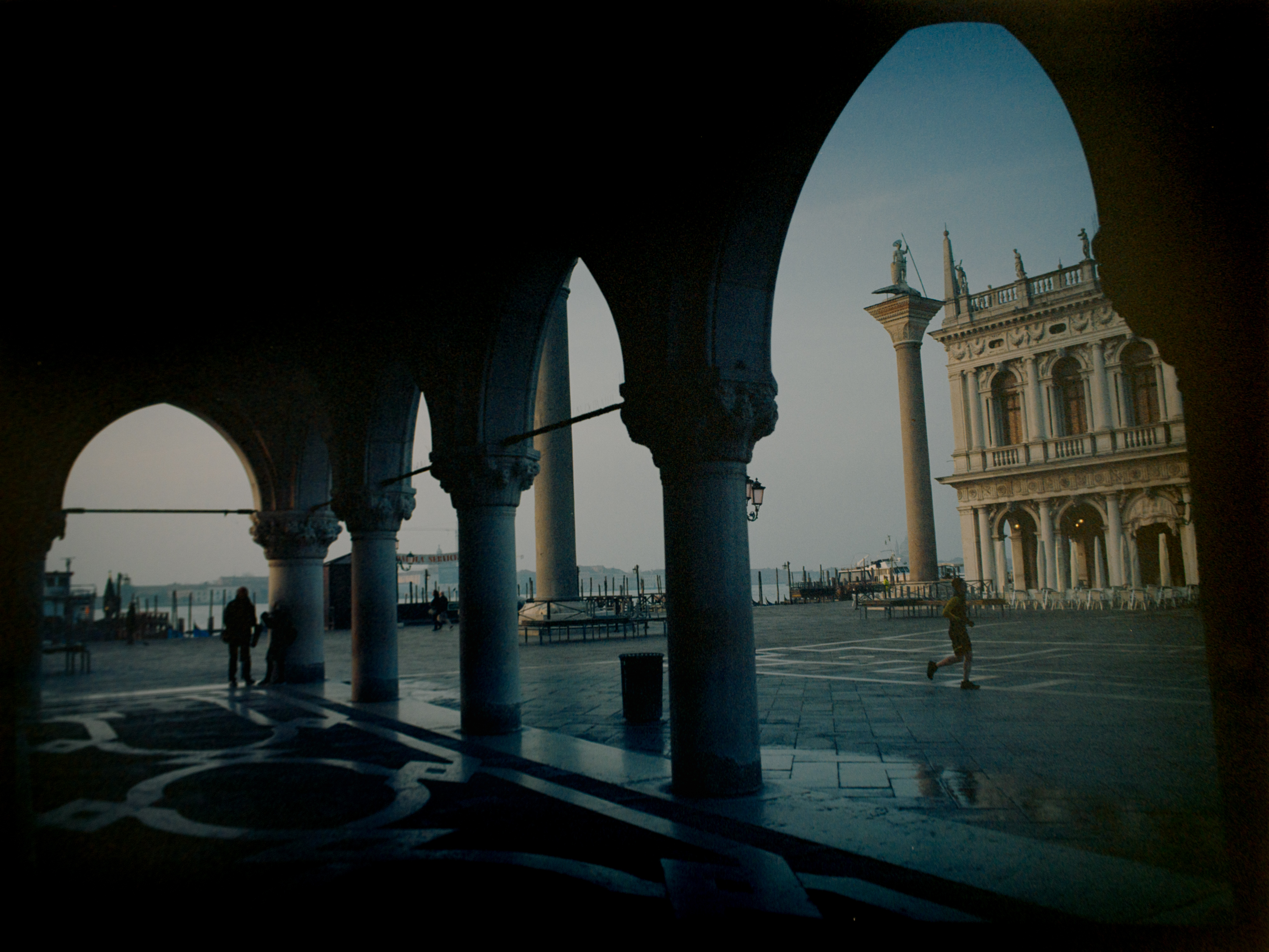 Wide horizontal view from the Doge's Palace arcade through multiple Gothic arches — Venice blue dusk on Ektar 100