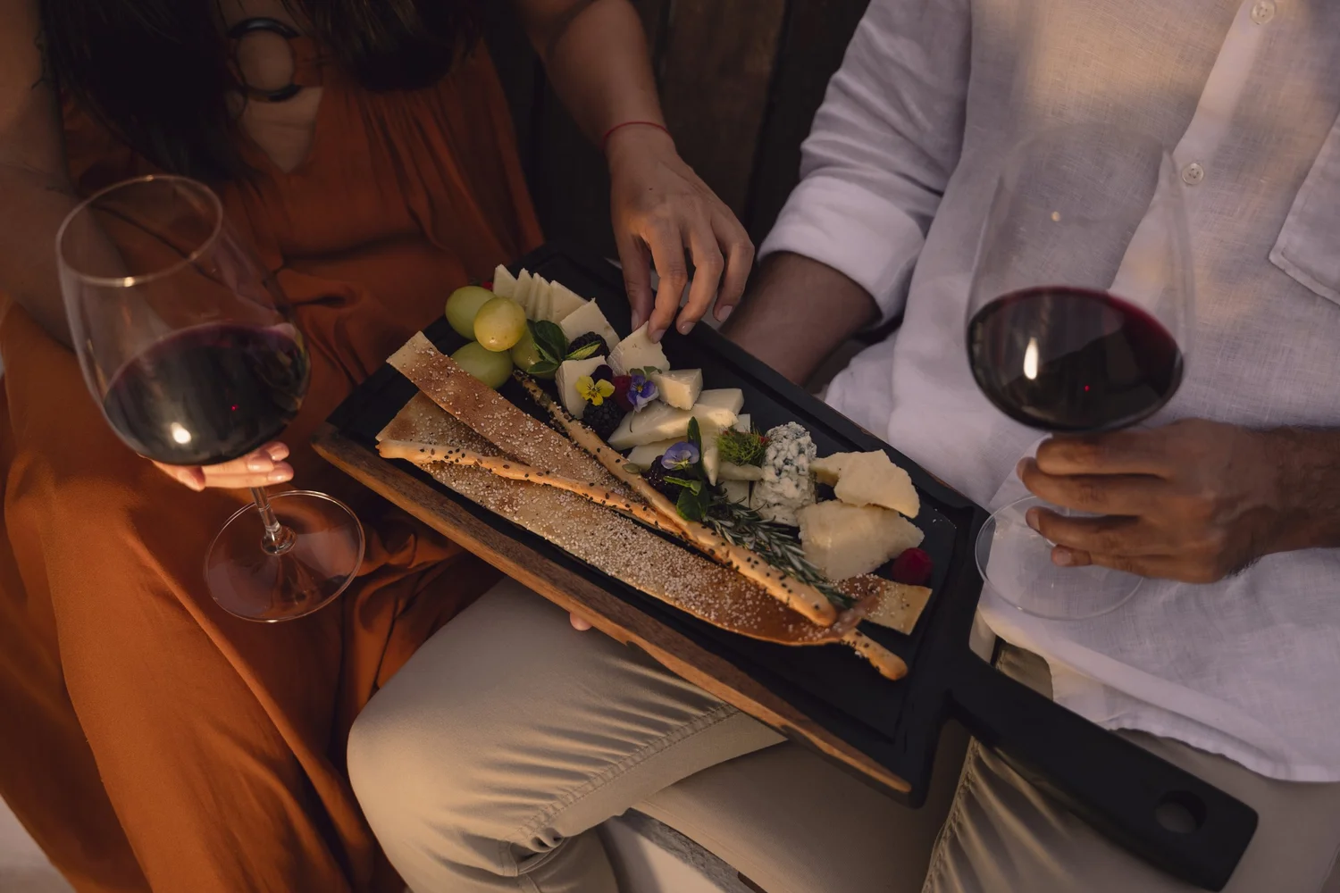 Couple sharing cheese board red wine warm lighting