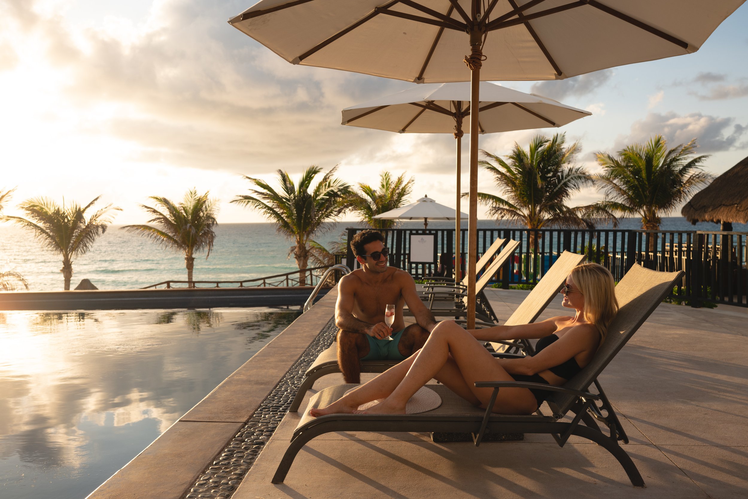 Couple poolside sunloungers sunset champagne ocean view, lifestyle photography London