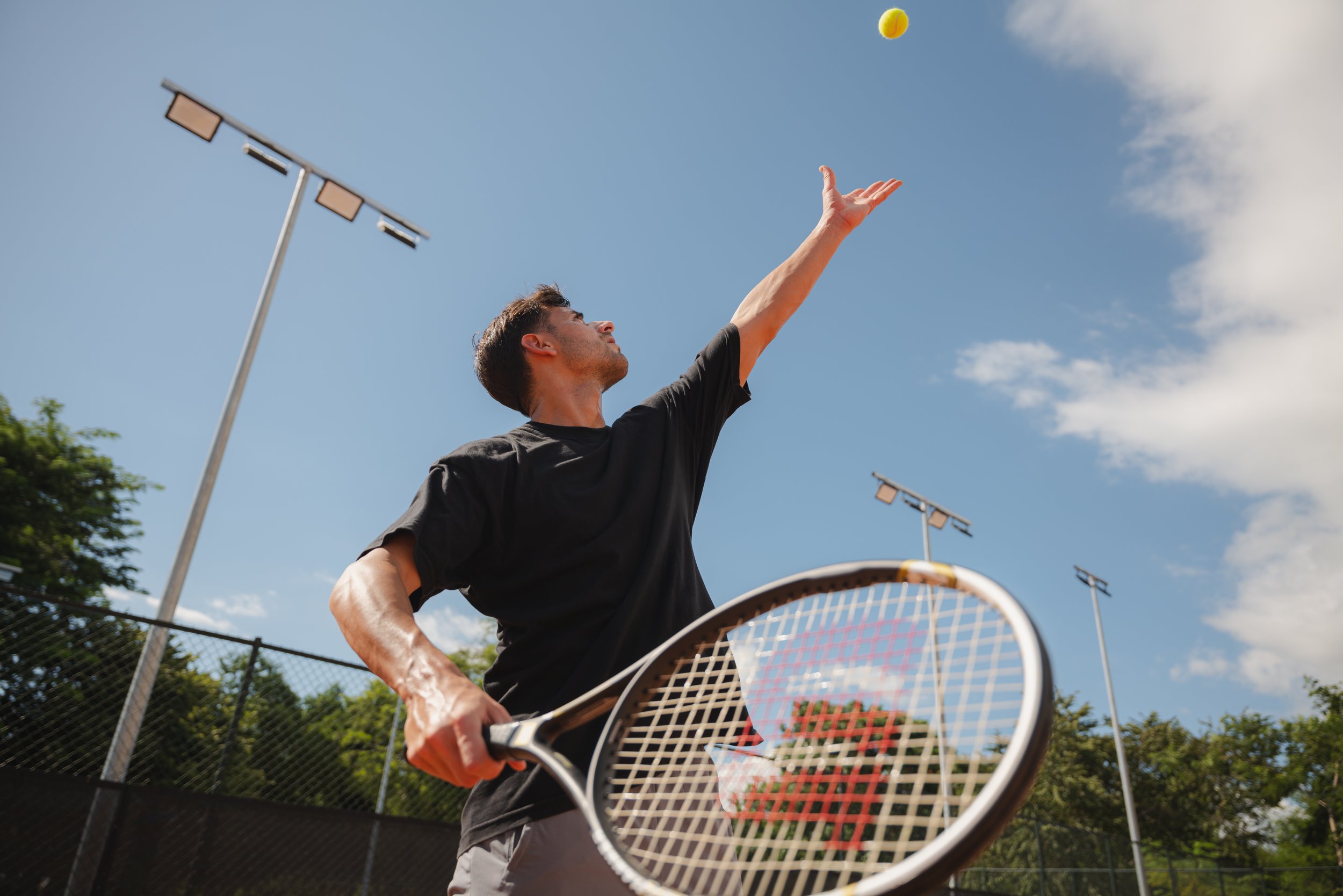Hotel guest tennis court serve, resort activities lifestyle photography
